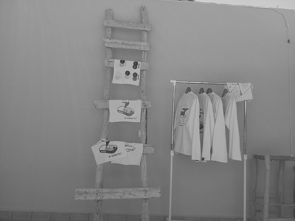 Tee-shirts accrochés sur un portant à côté d’une échelle, en noir et blanc