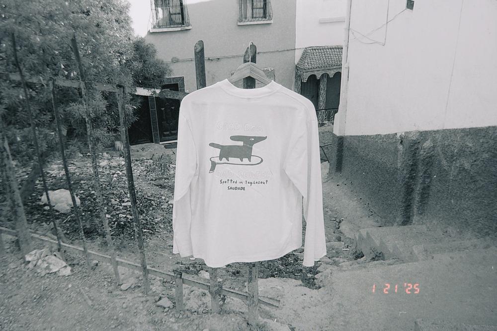 Tee-shirt Good dog, bad surfer accroché sur une grille, en noir et blanc