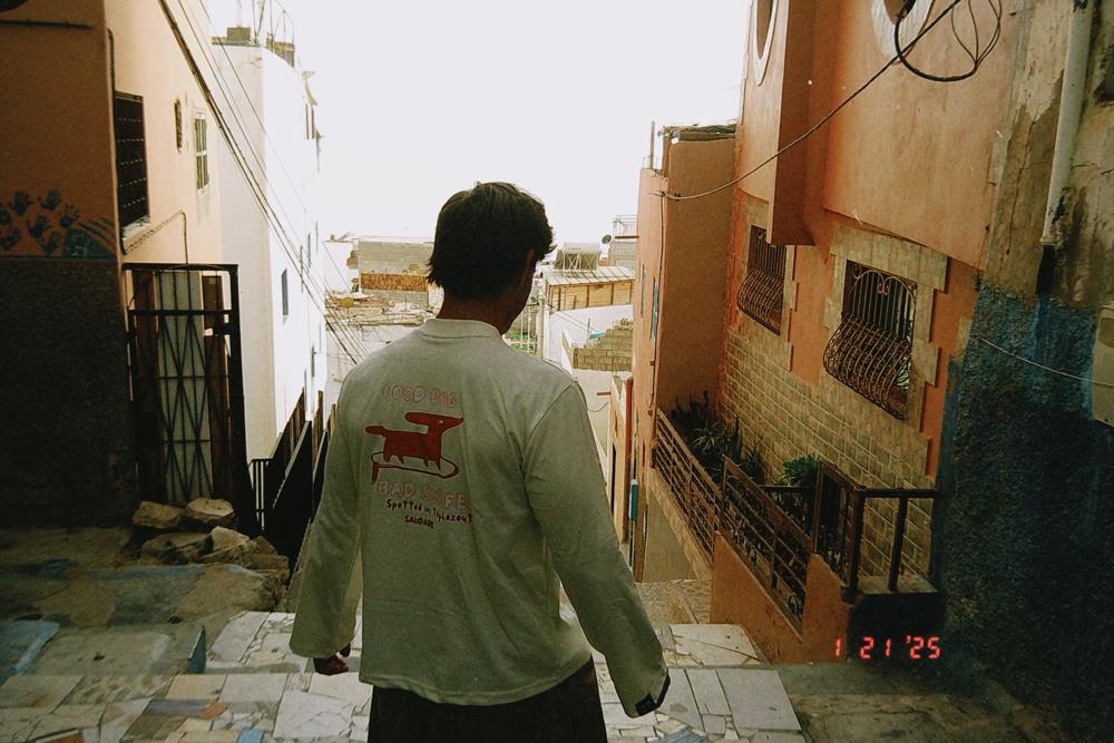 Tee-shirt Good dog, bad surfer porté de dos dans un escalier de Taghazout