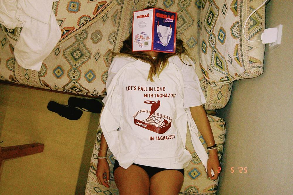Tee-shirt Let’s fall in love with Taghazout sur une personne allongée sur un canapé, un magazine sur le visage