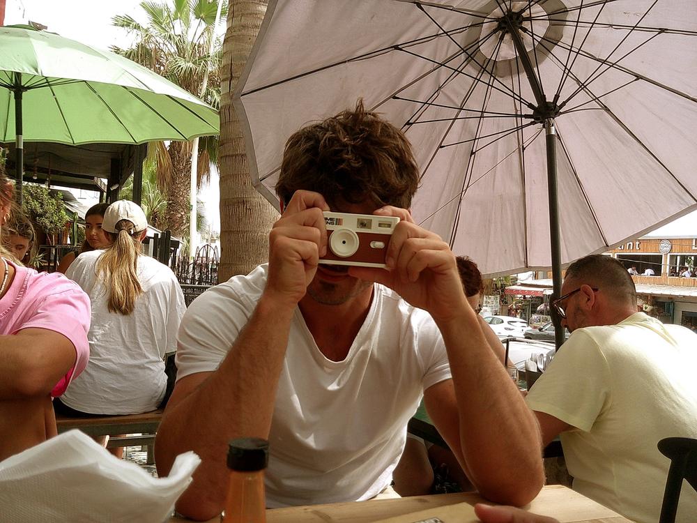Un homme prend une photo avec un appareil jetable à une terrasse