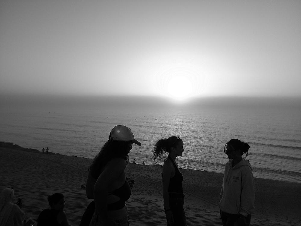 Silhouettes face au coucher de soleil sur l’océan, en noir et blanc