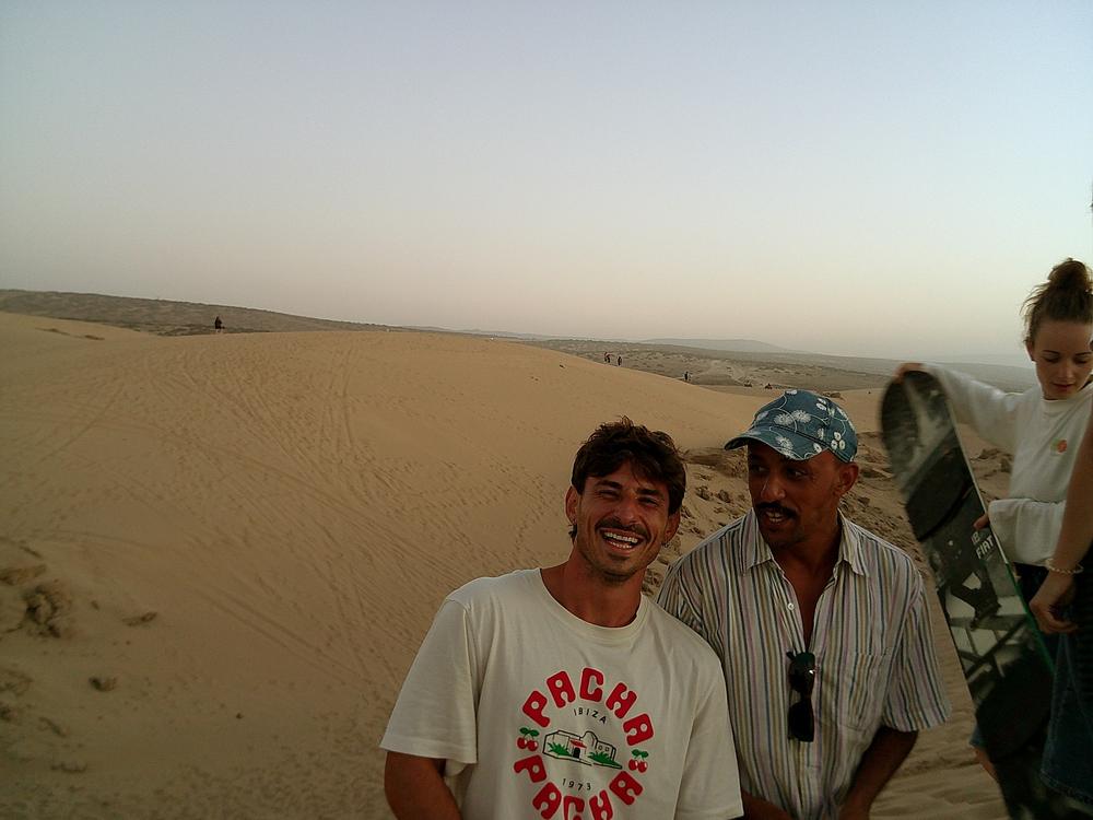 Rires sur les dunes, une planche de sandboard au premier plan