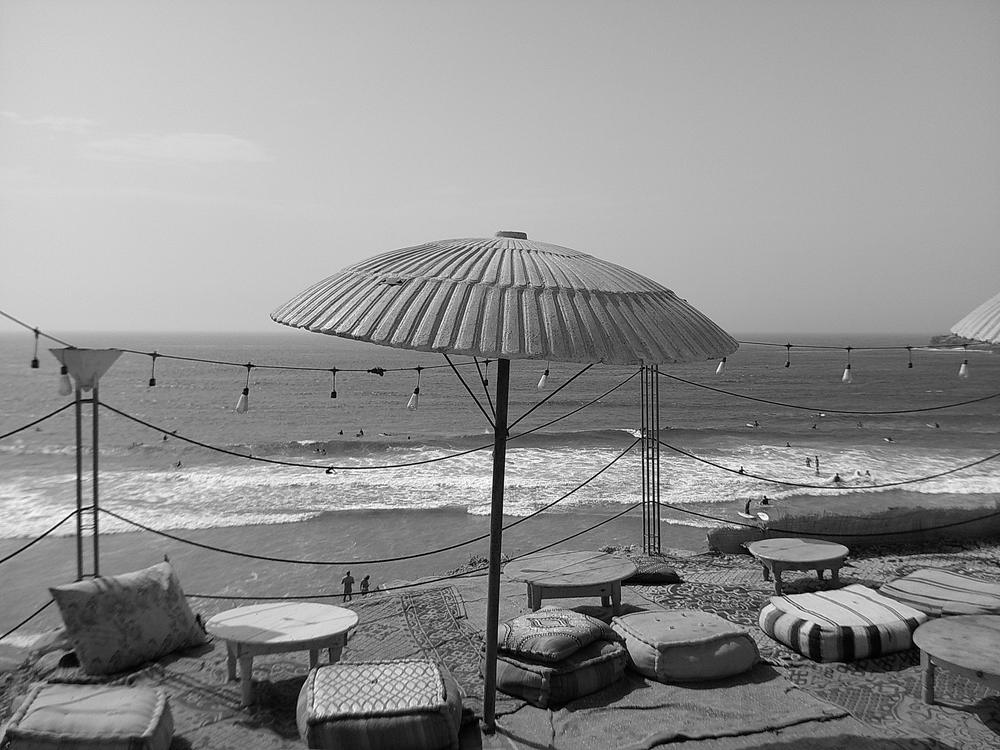Parasol et guirlandes lumineuses face aux vagues, en noir et blanc