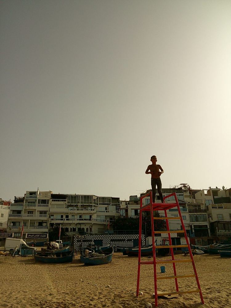 Silhouette sur la plage devant les façades, tour de sauvetage rouge