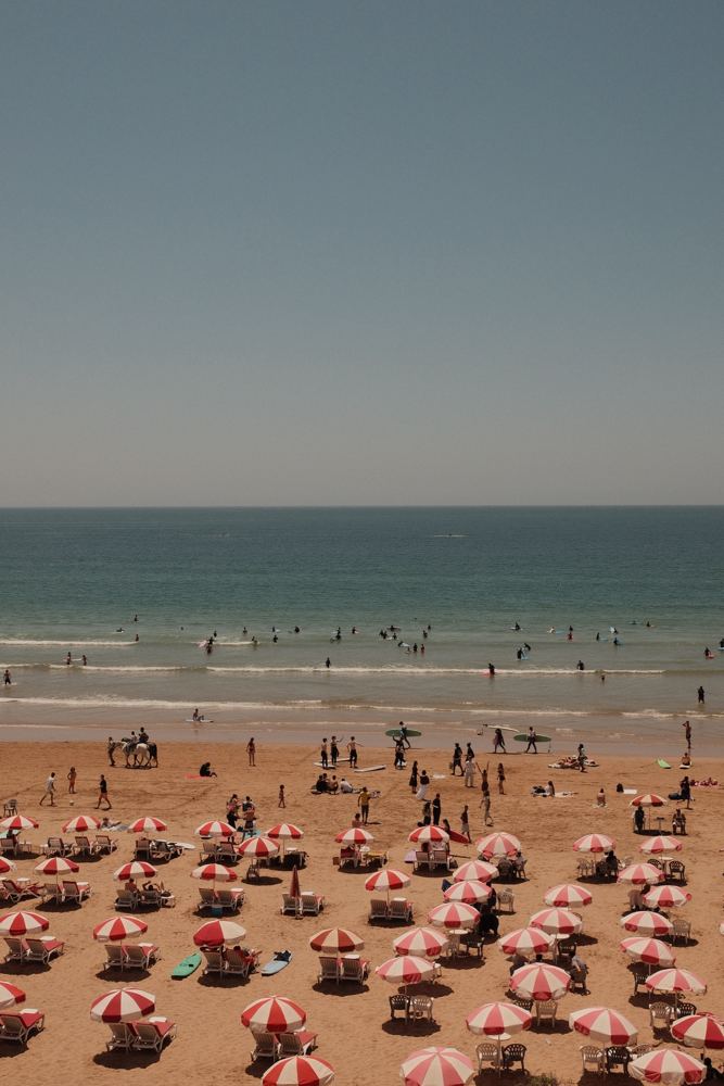Plage, parasols rouges et surfeurs dans l’eau