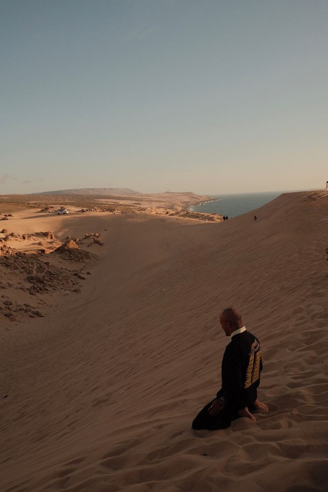 Assis dans le sable, regard vers la côte